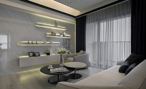 客厅
Living Room
客厅置入米色沙发及黑白双色圆形茶几,佐以洁白窗纱、玄色窗帘,与饰有俐落线条的沙发背牆,共组现代简约之美,而对侧的灰白纹理大理石牆则架设三层铁件层架,取代放置电视的位置,令业主能够自由佈置别具意义的相片与纪念品,展露深厚的亲子之情。
We arranged a beige sofa and a black & white nesting coffee table in the living room. Accompanied by the white sheer and inky drapery, the wall with neat trims behind the sofa presents the beauty of minimalism. Three levels of steel floating shelves installed on the white marble wall take place for the TV set and provide the owners to display memorable photos and decorations symbolizing profound family bonding.