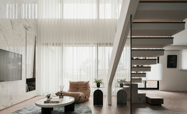 
客厅
Living Room

客厅以单椅取代量体较大的沙发，塑造轻盈柔和氛围，电视牆则令材质延续至玄关及二楼，提升整体性也拉高空间感，另于窗畔规划结合斜面造型的展示柜，供居者摆置装饰小物，增添生活趣味。

We replace bulkier sofas with single chairs to create a lightweight and inviting atmosphere in the living room. The use of materials extends seamlessly from the TV wall to the entryway and the second floor, enhancing the overall cohesion and creating the illusion of more space. Additionally, we cleverly arrange a display cabinet with a sloping shape by the window, allowing the owner to showcase personal items and adding a touch of whimsy and charm to daily life.

