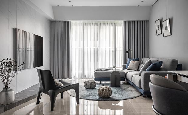 
客厅
Living room

类银狐石的电视牆以分割线条妆饰，打造俐落吸睛立面；灰色沙发搭配雾蓝绷布、抱枕与地毯，呼应餐橱柜色调，同时界定客厅空间，其背牆则做浅灰跳色粉刷，结合醒目的黑色单椅，共组雅緻景色。

The artificial marble TV wall with dividing linear features fashions a focal point of the living room. Then, we arrange gray sectional sofas and lay a few airy-blue throw pillows and an area rug to correspond to the sideboard. In addition, paint the back wall with a light-grey hue and furnish a striking jet-black single chair, resulting in an elegant scene.
