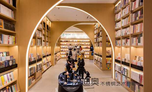 从地面一直延伸到天花的不锈钢金色木纹书架，弧形小半面屏风嵌入了明亮的灯带，一眼望去如同时光隧道。