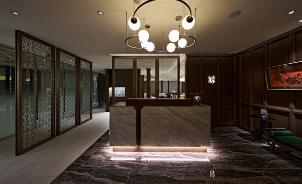 
柜台
Reception Counter

甫入餐厅，拼接金属边线和石纹的木质柜台立于玄色大理石地坪，予以访客们洗鍊大气的现代印象，一旁深色线凋木板则悬挂水墨花景画作，和对侧镂空的线纹屏风相应，为此处汇入典雅的中式美学。

Upon entering the restaurant, a refined reception desk crafted from rich wood, adorned with metal trims and stone accents, welcomed the guests, all set against the luxurious backdrop of black marble flooring that exudes contemporary sophistication. Adjacent to the reception, dark wood panel molding showcases an exquisite ink-wash floral painting, while an openwork screen on the opposite side artfully integrates elements of classical Chinese elegance.
