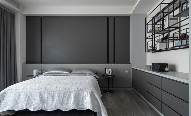 
次卧
Second Bedroom

男孩房床背牆施作光滑面烤漆，下方则镶嵌浅灰色绷布，达到良好的隔音效果，而牆面及旁侧收纳柜的线条造型，搭配柜体上方的铁件展示架，流露率性洗练风格，对侧的书桌背牆依循居者喜好，选用蓝灰色壁纸，呼应整体灰调，形塑和谐静谧的休眠场域。

For the boy's room, the bed wall was finished with smooth surface paint, while a light grey fabric was inset below to achieve good sound insulation. The line and form of the storage cabinets and display shelf above complement the laid-back and simplistic style of the resident. On the opposite wall, a smoky blue wallpaper was used to resonate the overall tone, crafting a harmoniously peaceful resting area.
