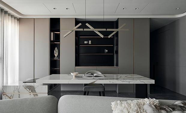 客厅
Living Room
有别于纯粹休憩机能的起居空间,屋主寄望客厅成为观影休閒、用餐接待与直播拍摄的多功能场域,因而此区摒除隔间,引入大片採光,放大空间坪效,并运用同一块大板砖,前后呼应连袂一致的视觉效果。为营造奢华大气氛围,将天花板上推进,并以金属板修饰梁柱,与镀钛元素调性相融。落地窗前搭造一玻璃屏风,化解进门穿堂的风水疑虑,亦成为入门后的独特端景。
The homeowner expected the living room to facilitate a home theater, a recreational space, and a live shooting studio rather than simply a resting space. As a result, an open layout design allows a great deal of natural light and shapes an expanding view, achieving a coherent image with a large slab tile. Besides, a high ceiling design complements a grand style as adorning panels on the column echo the metallic tone. Furthermore, a glass partition in front of the French window resolves the Feng-Shui taboo of door to window, presenting a distinctive feature view.
