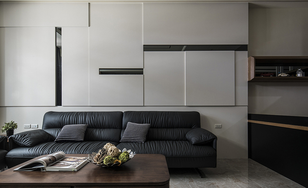 
客厅
Living Room

客厅的灰大理石电视牆，跳脱传统框线束缚，于两侧打造不对衬的立体区块，对面纯白色的木作沙发背牆，则镶嵌条形灰镜，运用深浅交错的纵横线条，表现时尚俐落感；望向家宅内部，餐厅前方半通透的灰玻屏风，其图腾以精细的CNC切割木质加工製成，为色彩纯粹的空间增添丰富层次。

The grey marble TV wall in the living room converts the stereotypical frame design into asymmetrical three-dimensional patterns on both sides. Inlay strip-shaped gray-tinted mirrors on the white wooden wall behind the sofa brilliantly present a neat stylish look through the staggered linear features. Adopt fine CNC machining to shape a whimsical totem on the transparent grey glass screen in front of the dining room, adding rich layers to the simple-toned space.
