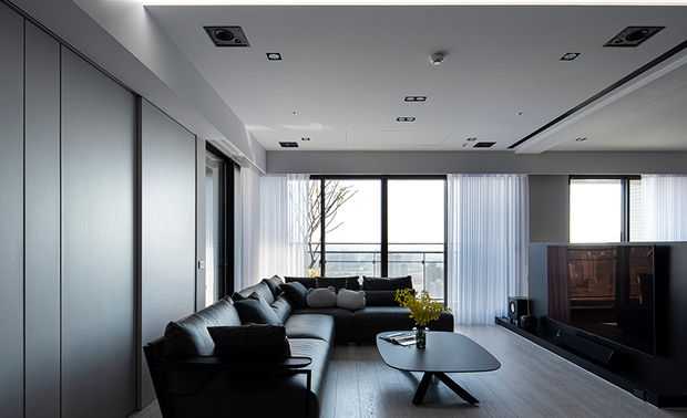 本文由OPEN编辑部撰写

设计概念 Design Concept

暖白灯光交映之下，温润的浅色木质地坪，与强调个性的黑色铁件、皮革，呈现简练而不失温度的居家画面，搭配一览无遗的窗外市景，共谱新婚生活的美好序曲。

乔艺设计 王沁凌 设计总监 善用毛胚屋装修自由的特性，重新梳理格局，增加夫妻二人相处同乐的空间，划设造型俐落的斜切角天花板、多边形书桌，并不时点缀中和冷冽调性的灰、白色彩，构筑一座都会感十足的舒适家宅。

The warm-white lighting, the balmy pale wood flooring, the unique black ironwork furniture, and the leather element agreeably manifest a pristine yet warm picture of the home. Then, together with the captivating urbanscape, marvelously start a beautiful prelude of newlywed life.

Taking advantage of an unfinished house, which can plan at will, Chiauyi Interior Decoration Design design director Linda Wang re-configures the layouts to expand the spaces for the couples to get along and have fun. Set up sleek chamfered ceilings, place an unusual polygonal desk, and adopt pastel gray and white color schemes to moderate the chill base tone, successfully creating a comfortable and fashionable home.

设计手法 Design Techniques

纯粹色调 巧变氛围
Clear color schemes ingeniously bring about an agreeable, homey ambiance

沉稳的黑灰白三色硬、软装，搭配铺设全屋的木纹石塑地坪，在冷暖光源的转换下，平衡空间的深浅色系，营造多变氛围，例如时尚简约的客厅、书房，与盈溢温馨气息的餐厅，既满足业主的色彩喜好，亦保有家宅的温度。

The stable black, gray, and white furniture and furnishings, assort with the wood-grain stone plastic flooring, well balance the color shades of the space, moreover, bring variable ambiances through the changes of cold and warm lighting. And the patterns of the stylish living room, the concise study nook, and the inviting dining area strikingly satisfy the homeowners' preferences and hold the warmth of a home as well.

简约线条 现代时尚
Concise linear features result in a modern, refined space

公领域中，天花板简洁有力的斜切角造型，与内嵌其中的铝条灯，一同勾勒时尚风貌；下方带有弧形圆角的茶几、餐桌椅等家具，则平衡周围方正的收纳柜体及牆面，一刚一柔相互交织，丰盈场域的线条层次。

The chamfered ceiling of pared-down form and the recessed aluminum strip lights in the shared areas draw fashionable features. In addition, the curve edge furniture such as the coffee table, dining table, and dining chairs coordinate the surrounding square storage cabinets, interwoven with rigidity and softness, and enrich the linear gradation of the space.

通透格局 宽敞视野
See-through layouts lead to a capacious, unimpeded vision

配合业主的生活习惯，以吧台取代原有的厨房隔牆，划设开放式餐厨区域，构筑宽敞通透的格局，并调换书房及餐厅的位置，摆入兼作电脑桌的多边形书桌，让兴趣相投的夫妻两人，能于此同享电玩游戏的欢乐时光。

Demolish the partition wall of the kitchen and replace it with an island; skillfully set up a spacious, transparent, open-patterned kitchen-dining area. And flip the original layouts of the study and dining area to fit the living habits of the householders. Place a polygonal table at the study that also serves as a computer desk so that the couple with similar interests can enjoy the happy hours of playing online games here.
