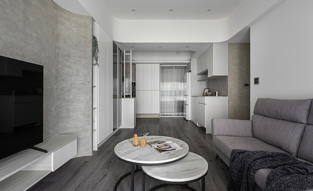 
本文由OPEN编辑部撰写

设计概念 Design Concept

日光漫照，转眼充盈整间淨白家居，流淌于圆润曲弧和俐落线条间，轻抚壁面细腻的纹理、点亮每格将填满回忆的展示柜，构筑一幅简练纯淨的美好风景，静待一家四口引领生活进驻，为此新添清脆的朗朗笑语。

回应业主的收纳需求与对现代风格的喜爱，棠禾设计 曾智和 设计总监 善用宅内各处空间并配置大量柜体，另将「洁淨、俐落、无压」作为关键词，公领域以灰、白主色搭衬品牌主打的暖意木纹，围塑敞亮舒适的起居环境，卧房则依居者喜好，打造拥有个人色彩的一方天地，予以每个人机能充裕的理想美域。

As sunlight gracefully bathes the space, it fills the pristine home. Adopt smooth curves and elegant lines, exploit delicate textures on the walls, and brighten every display cabinet where memories reside. We create a simple, refined, beautiful scene for the family to live in, bringing cheerful laughter that starts a new chapter in life.

Considering the homeowner’s need for ample storage and a love for modern aesthetics, Tang He Design’s design director TSENG CHIH HE skillfully utilizes every nook and cranny, incorporating numerous cabinets. Taking “clean, sleek, and peaceful” as guiding principles, we adorned the communal spaces in a gray-white color palette, complemented by the balmy wood tones that define our brand, which creates a clear and inviting living environment. Bedrooms are tailored to the user’s preference, crafting personalized havens that provide an ideal and functional retreat for the room users.

设计手法 Design Techniques

灰白盈室 曲弧溢柔
Elegant Curved Feature: Soft Harmony of Gray and White

本案以纯白搭配灰色艺术漆，辅以线条元素，共组清爽俐落的现代风情；公领域天壁汇入曲弧元素，与曲面电视牆相呼应之馀，更添一抹柔和韵味，结合满载暖意的木地坪、深色调软装，营造敞亮温馨家居。

We skillfully exploited a palette of pure white paired with gray artistic coating, complemented by sleek linear elements, bringing about a refreshing and modern ambiance. Then, ingeniously incorporated the curved elements into the ceiling in the public areas, working in concert with the curvilinear feature of the TV wall, gently adding softness and charm to the place. Moreover, we integrate balmy wooden flooring and deep-toned furnishings, which achieve a bright and cozy home filled with warmth.

巧配机能 灵活空间
Smart Solution: Flexible Setting for Compact Living

因应案场坪数偏小，餐厅选用设有滑轮的机能餐桌，平时可收进餐边柜，释出宽敞动线，日后若想摆放正式桌椅，可撤除活动式餐桌，并于收纳处加装隔板改为展示柜，保有使用的自由度，而旁侧厨房入口设置一面长虹玻璃滑门，烹饪时能隔绝油烟，平时则维持敞开，营造宽阔空间感。

We meticulously set up a functional dining table with casters to resolve the cramped room issue. It can be easily tucked into the dining sideboard, freeing up ample space. Should the need arise for a formal dining setup, the mobile dining table can be removed, and the storage space can be equipped with panels to transform into a display cabinet, providing sufficient flexibility for the homeowner. Additionally, we thoughtfully arranged a reeded glass sliding door at the kitchen entrance to cut off gross smells when cooking, and it can be kept open to give unimpeded views on ordinary days.

各具风格 人本关怀
Distinctive Style: Human-Centered Design

私领域依据每位家庭成员的喜好打造卧房，主卧一改公共空间风格，以温馨的木色为主，给予业主夫妻放鬆的舒眠环境，两间次卧则採用居者挑选的色彩妆点床头牆，展现各自的独特品味，此外，全案皆选用绿建材标章的系统板材，搭配无甲醛涂料，共创健康无毒的天伦生活。

In the private quarters, each bedroom is tailored to the preferences of every family member. The master bedroom featured warm wooden tones to create a relaxing sleeping sanctuary for the couple, departing from the concise style in the shared areas. The homeowners opt for their favored color to finish the accent walls of two secondary bedrooms, showcasing their unique tastes. Additionally, we utilized engineered panels certified with green labels, complemented by formaldehyde-free paint, contributing to a healthy and toxin-free family living environment.
