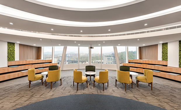 
接待大厅
Reception Area

接待大厅的弧形柜台、地毯上企业识别色的圆形色块，双双呼应铜钱意象及圆满理念，柜后于窗畔两侧划设阶梯式等待区，结合户外美景，成为适合员工歇息和公司举办大型活动、聚会的舒适空间。

The reception area showcases a gracefully curved counter and circular color blocks in the corporate hues adorning the carpet, harmoniously echoing the imagery of a coin and the concept of completeness. Behind the counter, tiered seating areas flank the windows, seamlessly integrating with the outdoor scenery to create a welcoming and comfortable space. This designed area exceptionally provides a serene resting spot for employees and an ideal venue for the company to host large-scale events and gatherings.
