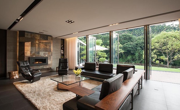 客餐厅
The living room and the dining area
自玄关进入客厅,右侧为透过烤漆隐藏的电视柜和展示柜,左侧则为瓦斯壁炉,不仅有除湿之效,更温暖居者身心。天花板上两条平行槽线,导引视线由客厅、餐厅直至尾端吧檯区,使格局更显贯通。
客厅的部分露台悬空,玻璃推拉门的运用转换住家角度,将设计自休憩别墅方向出发,落实沉醉自然的度假风;敞开的落地门使内外空间合而为一,屋体静立大块之中,静待风的流淌为其宁静增色,与其相融相生。
While entering the living room from the foyer, on the right side, the TV wall and the built-in display shelves, which perfectly integrate by way of the baking varnish, it also can well conceal the TV set and the collections; and on the left side, set up a gas fireplace, which not only has the effect of dehumidification, but also brings warmth for the people who live here. Two parallel recessed-light grooves on the ceiling guide the sight from the living room, the dining area to the bar at the bottom, so as to create the capacious pattern.
Part of the terrace of the living room is dangling; make use of the glass sliding doors to create the natural resort style; the setting of the open French windows integrate the internal and external space. The building is standing amid the magnificent land, and the breeze gently flows; hence bring about the tranquil and leisure circumstance.