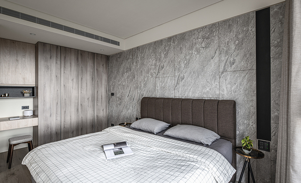 
主卧
Master bedroom

主卧的木作床头牆面贴石纹美耐板，藉由整齐乾淨的拼接线条，巧妙融入卫浴隐藏门轮廓；临窗处设计直条式黑色灯沟，内嵌线型灯条，增添美感变化与浪漫氛围，一旁与空间色彩相互协调的灰、白寝具，则配饰咖啡色床背板，注入就寝时的温馨暖意。

Laminate the main bedroom's bedside wall with printed PVC marble panels, which artfully integrate the Ensuite bathroom secret door through neat and clean splicing lines. Embed a strip light into the vertical-shaped black notch near the window to enhance the glamorous feature and romantic vibe. Arrange gray and white beddings that tone in the surrounding color scheme, and assort with a brown padded headboard to introduce pleasant coziness to the sleeping area.
