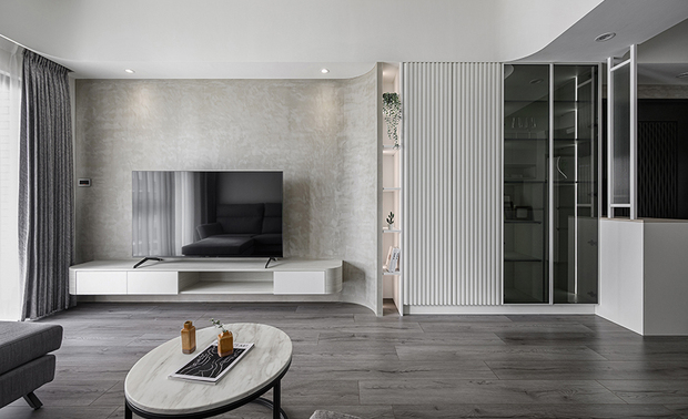 
客厅
Living Room

素淨的客厅搭衬灰色系家具及电视牆，予人怡然舒适的氛围，比邻的展示收纳柜延续线条元素，并于内部加装线灯，更加凸显业主的藏品与家庭回忆。

The serene living room is adorned with gray-toned furniture and a matching TV wall, resulting in a homely and comfortable living room. Adjacent to it, the storage display cabinet extends clean linear features with embedded strip lights, accentuating the homeowner’s cherished collectibles and family memories.
