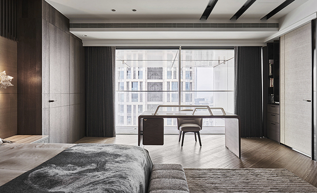 男主卧
The male host’s bedroom

卧房铺设舒适温暖的海岛型木地板，并以斜拼方式延伸整体视觉感受，床头牆採用部份木皮格栅，呼应客厅沙发基座的材质，侧牆摆设精品丝巾製成的画框，让艺术画作成为空间的重点元素；窗边设置简约造型的书桌，其悬空的抽屉构造更显轻巧便利。

Pave diagonal-pattern engineered flooring to bring a warm and cozy situation to the male host bedroom. Then, finish the top of the headboard wall with a wooden grille setting to correspond to the living room wooden sofa base. Use an exquisite silk scarf to make an artistic hang painting, which becomes a striking feature of the space. Also, arrange a simple, stylish desk by the window, and through the suspended drawer design, make it looks delicate and handy to use.
