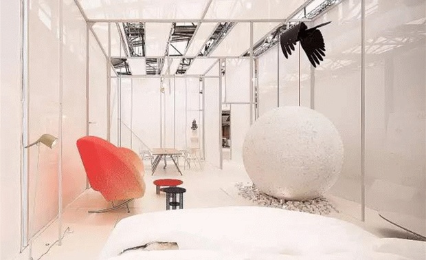 一个80㎡的展馆设计项目。选择了半透明广告网格布和钢结构相结合搭建房子外立面的设计。半透明的封闭空间，能有效地分流展会里密集的人群，使杂乱的大环境变成相对安静有序的小环境，同时室内与室外的人又不会完全隔离，彼此间还可以相互感受到存在，静中又有“动”的状态，会让参展的人在轻松中又有一种紧张感，让有目标而来的人不自觉地提高办事的效率。
在具体的空间内，我设置了一个泡沫做的、带有凹凸质感的大球体，与悬浮在半空中的小鸟一起形成了一个黑白对比、动静互应的感觉。一张柔软的床，一张舒适的办公桌，一张漂亮的沙发，一个纯白的环境，干练中透着舒适，极简中透着精致，且能让每个角落都隐藏着供人发现的画面感。