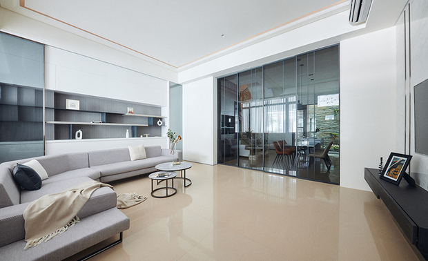 
客、餐厅
Living-Dining Rooms

客厅的银狐大理石电视牆，内嵌两道镀钛金属线条，为其清新纹理注入细腻光泽，造型朴实的灰色沙发和茶几，则契合全屋的简雅调性，其后方展示柜，另加装一面活动式灰玻门片，与同材质的餐厅推拉门遥相对应，呈现半通透的视觉效果，一同丰富淨白空间的层次感。

Embed two titanium-plated lines into the Ariston Kalliston marble TV wall, adding a delicate luster to its fresh texture. Then, arrange simple grey sectional sofas and a stylish coffee table perfectly agree with the pared-down form and elegant tone of the whole house. Erect a detachable gray-tinted glass door to the display cabinet behind the sofa, dimly creating a transparent visual effect. Moreover, it works in concert with the sliding door of the dining room through identical materials and enhances the layering features of the clean, white space together.
