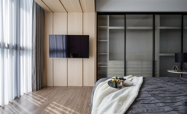 主卧房 The master bedroom

主卧房色调与起居空间遥相呼应，
低调沉静的色彩，回归场域休憩本质。
其中增设的修饰大樑，沿着天花板落地，
彷彿一道景框，框塑出空间情境。
床头背板的普鲁士蓝，与临窗处的暖黄单椅，也为整体氛围增添活泼色彩。

The hue of the master bedroom echoes the living area; the low-key and tranquil tinge brings the reposeful feature into the space.
The additional decorative T girder along the ceiling way down to the floor, as framing a landscape and shapes the distinct spatial situation.
The Prussian blue of the headboard and the cozy yellow single chair near the window, both add up vivid color to the overall atmosphere.
