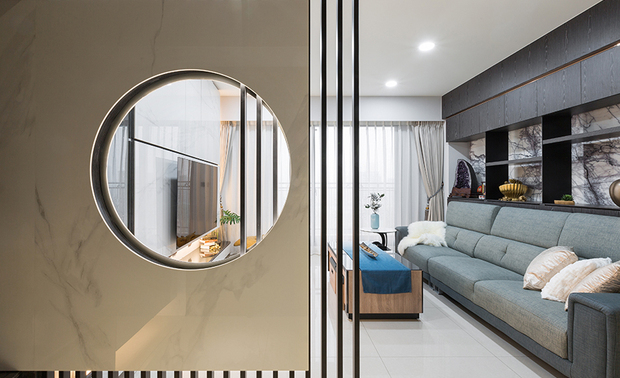 本文由OPEN编辑部撰写
设计概念Design Concept
柔和的环形光晕从屏风中流泻,与窗外和煦日阳相映生辉,犹如佛祖广纳世人的包容性,为皑白陶板与深褐木质晕染上温柔气息;信步入内,廊道转角处的神桌溢散红光,衬托佛像的庄严,诚心礼佛、摒却杂念,带着虔诚之心,安处于平静恬澹的生活场域。
艾美幸福设计 许捷甯 设计总监 将「禅」纳入空间的每个角落,巧妙地运用简约的黑、灰、白色建材,结合温润柔和的陶板、纹理大气的石材、坚硬刚强的铁件与质朴温煦的木质,彼此交融、互补,正如佛教所谓「因缘和合」,人与环境最终达至一个「圆满」的状态。
The soft circular halo flows from the screen and complements the warm sunshine. The white ceramic panel and dark brown wood grill setting represent the magnanimous tolerance of Buddha and emit a calm vibe. At the corner of the corridor, the home Buddhist shrine sets off the solemnity of the Buddha statue, the householders sincerely worshipping the Buddha, getting rid of distractions, and settling in a peaceful and tranquil situation with a devout heart.
Amy Studio design director Amy Hsu spreads Zen-like features around the space. Ingeniously utilize the simple black, gray, and white toned building materials, and assort with warm, gentle ceramic panels, glamorous textured marbles, steady vigorous iron parts, and rustic balmy timbers, which are well-proportioned and complement each other. Just like the so-called "Union of causes and conditions" in Buddhism, people and the environment eventually reach a state of "perfection."
设计手法Design Techniques
东方禅风 黑白沉静
The calm black-white tone reveals the Oriental Zen-like ambiance
考量业主的佛学信仰与喜好,全室色调以黑、灰、白作为基底,硬装选材从润白的陶板、黑白纹理交织的大理石,到深褐色的木质,用色与质地上相互融合,打造沉稳宁静的氛围,佐以灰蓝色系软装,为肃静的公领域增添自然气息,达至动静和谐之禅意。
Considering the homeowner's Buddhist belief and taste, we adopt black, gray, and white as the base tone. Select polished white ceramic panels, glamorous white marble with vivid black veins, and dark brown wood to fashion the space. Skillfully integrate the colors and textures to bring a calm and serene atmosphere. In addition, arrange mist blue home furnishings, which enrich a natural ambiance to the composed public area and achieve a harmonious Zen implication between liveliness and stillness.
陶石相间 遥相呼应
The splendid ceramic-marble patterns marvelously correspond to each other
结合收纳功能的电视牆,採用白色陶板作为柜门,轻巧、简约仍保有厚度的质感,能使门板五金长久使用;对面的沙发背柜,其后方立面为来自西班牙的大理石「纽约纽约」,由业主亲自遴选,带有强烈的线条与凋刻质感,即使作为柜体背景,仍不减其风华;两种建材相互应和、配置得宜,为公领域奠定和谐的主视觉。
The TV wall with a storage feature shows a lightweight and sleek pattern through white ceramic cabinet doors, which are excellent for long-term usage. Exploit a New York marble polished slab to finish the wall at the rear of the sofa, which is imported from Spain and personally selected by the homeowner. The glamorous veiny pattern becomes an elegant focal feature behind the wall-mounted shelves. The two well-arranged building materials marvelously complement each other, creating a harmonious situation in the public domain.
信仰中心 机能巧思
The crafted arrangement with unique features accomplishes the hub of family beliefs
位于餐桌斜角的神明桌,作为全家人的信仰中心,其文公尺的丈量、吉祥基数的讲究、收放自如的机能性到全手工木作,皆与业主、风水师讨论规划,由木工师傅打造出独一无二的神桌,不仅外观庄严肃穆,内部装置更为讲究,除了基础收纳空间,另将桌面设计为镂空造型,置入红色玻璃与间接照明,开灯后发散的红光可作为神明灯,使上方佛像更显庄重。
We meticulously discuss and plan with the proprietor and the geomancer, use the carpenter's ruler to measure angles, pay attention to lucky numbers and flexible functionalities, and masterly make a unique handcrafted home shrine adjacent to the dining table to serve the family beliefs. We set up a stately look and required storage spaces. Moreover, mount red-tinted glass on the hollow-patterned tabletop and install indirect lighting to serve as the Buddhist lamp, shining on the significant Buddha statue.
