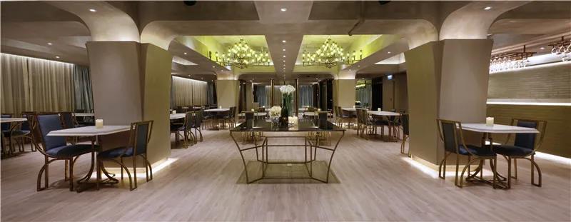 本案位于香港鸿图中心，餐厅的空间充裕，却有数量不少的横梁和结构柱，爲此设计师将梁柱设计成为装饰品，额外加建灯壳和灯槽，减少压抑而且更具美感。餐厅的设计简约，天花保留水泥的原色，加上那盏巨型的酒樽吊灯，带出一点欧洲古堡的韵味；搭配云石桌子和舒适的椅子，体验粗矿与细致的完美结合，创造出舒适的用餐环境。
餐厅的一侧是一字型的吧台，采用金色砖墙堆砌，呈现出低调而奢华的感觉，其亮面的外观在视觉上扩大了餐厅的空间感。设计师在吧台的上方设计了一排酒杯架，细心一看，里面暗藏灯泡，酒杯架也是灯饰，实用而美观，看上去极具现代感。
内设计有3间贵宾房，设计师纯粹以通透的玻璃造型门作划分，既可封闭又可敞开。不同区域之间没有了墙体的隔断，展现出空间的穿透感，延伸出开阔的视野。