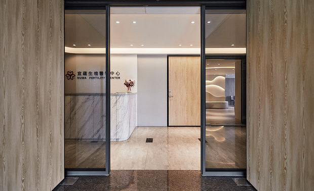 
入口外观
The featured entrance

入口处呼应迎接新生命到来的气氛，结合商标的木皮，溢散出带着暖意的温馨感；基于安全考量，门片採灰色玻璃，使人能清楚看见诊所柜台，又能清楚辨识自动门。

The featured entrance utilizes wooden panels to reveal a warmhearted feeling that responds to the delightful atmosphere of welcoming newborn babies. For safety reasons, we make use of transparent gray glass to set the automatic door, so that people can clearly see the reception counter.
