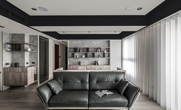 
客厅、书房
Open plan living room with a study

由于业主需居家办公，客厅后方以半高背牆隔出书房，并沿用天花板的深浅配色，分别于两处选用黑色沙发与浅灰单椅；两相对立的电视牆及书架牆，均以灰色石纹为基底，装设造型轻巧的悬空吊柜，并于窗畔对称规划花纹轻浅白色立柜，协调材质与色彩的变化性。

Erect a half-height partition wall to configure an adjoined study to the living room to meet the homeowner's need for working from home. Then select a black sofa and light gray single chairs to work in concert with the dark-pale color scheme of the ceiling. Set the TV wall and the opposite built-in bookshelf back wall with gray marble. Moreover, fix lightweight floating wall-mounted racks and the TV stand, and symmetrically arrange pastel white storage cabinets beside the windows, excellently integrating the varied materials and colors.
