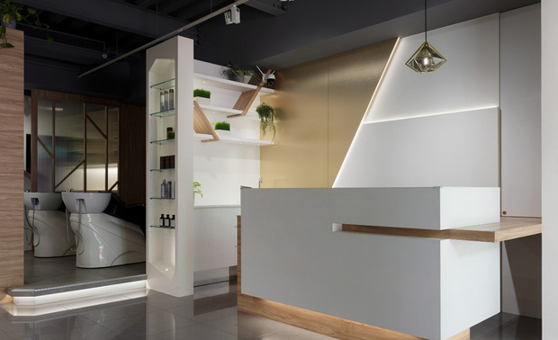 柜台
Reception Area

柜台嵌入木质平台提供客人暂放物品，后方的三角色块与层叠造型增添视觉层次，而旁侧的展示柜内藉木纹层板呼应「斜角」主轴，下方规划为茶水槽和茶点柜，便于员工接待来客。

An extended wood panel design provides customers with a drop space. On the back of the counter, the geometric shapes implement distinctive layering. Besides, the wood boards on the open shelving echo the slant feature. A small wet bar with cabinetry facilitates the staff's serving of tea and snacks to the customers.