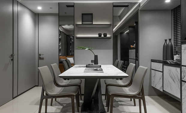 
餐厅
Dining Room

为改善餐区格局比例，我们设置两道灰玻，放大场域视觉，搭配浅灰色系家居，整体空间感受更显轻盈透亮。后方柜体悬空而设，下方提供给屋主放置扫地机器人，檯面上方则摆放咖啡机与花器，将使用频率高的机能融汇于此。而牆面一侧则简易设计层架，让女主人的藏品能予以展示，生活裡围绕着的，都是喜欢的事物。

We artfully decorate two gray-tinted glasses to create the illusion of more space, coupled with the light-gray-tinge setting, bringing a lightweight and concise look and visually refurbishing the layout of the dining area. Behind the dining table, deliberately install a wall-mounted cabinet. Leave the space for the homeowner to place a charging base of the robot vacuum below and display the coffee maker and flower vases on the countertop, perfectly bringing a well-functioning nook. Additionally, we meticulously set up open shelves on the wall beside the dining table, allowing the female owner to demonstrate her personal items. What a joy of life surrounded by all the things you like!
