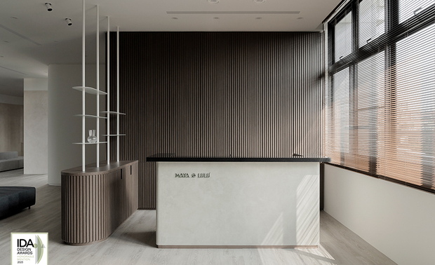 ▲入口柜体以大地色系特殊涂料铺叙沉稳底蕴，迎宾区域廊道则选用灰白色调，营造宁静舒心的过渡场域。接待柜台右侧大面窗引入自然光，与背后格栅式的实木条映照出阴影变化，衬托出自然温润质感。
