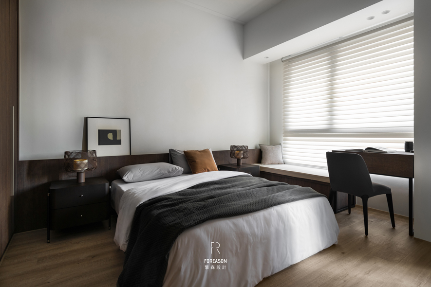 
卧室——宁静私语的安眠之所

卧室是经历一天疲惫后最柔软的归处。深色木质床头板沿窗边延伸，串联卧榻与书桌，形成完整流畅的色带。每日清晨，自然光透过百叶帘在纯白床铺上洒下光影，轻柔唤醒沉睡身心；入夜后，床头小灯伴随翻书声，思绪随之慢慢沉淀。窗边卧榻成为居者独处时锺爱的角落——可倚着抱枕看书、望窗发呆，或在午后阳光中小憩。于此，时间流动得格外缓慢，给予身心妥帖的安顿。
