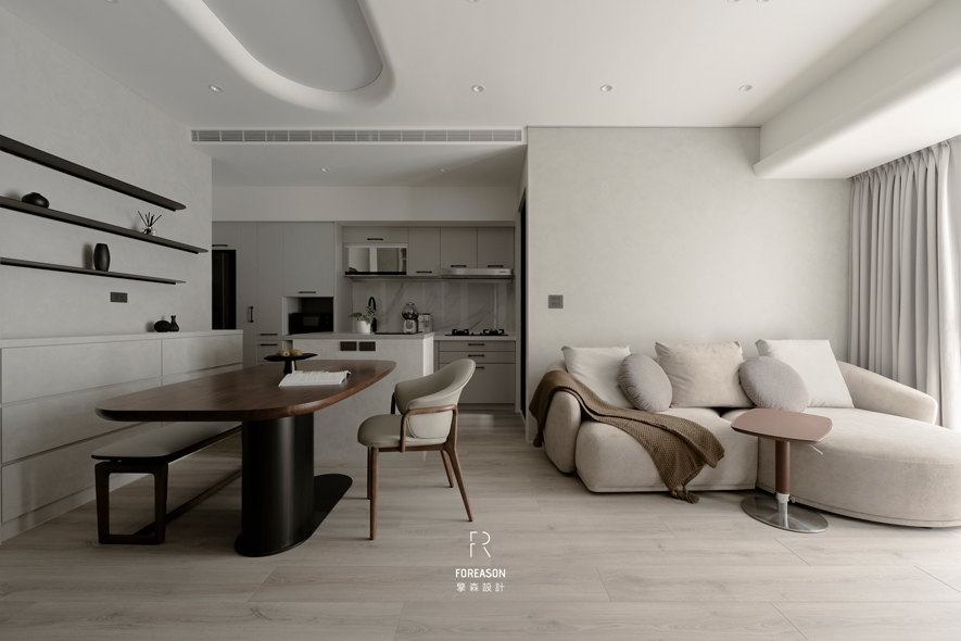 
本文由OPEN编辑部撰写

低调色系细腻质感碰撞 雕琢放鬆身心的当代空间！

当线条褪去繁复，材质回归本真，空间便显得纯粹。灰阶如晨雾轻笼，原木似暖阳轻抚，光影于通透格局中自在游走，视线不受阻隔，而是被温柔地引领——从此处漫步至彼方，每个转身都是风景。开放式厨房以简练手法勾勒，延伸至一旁的餐桌区域，黑色桌脚配衬温润木质桌面，刚与柔在此相遇、和解，谱写只属于这个家的独特个性。

擎森设计 设计总监 陈楚扉 洞悉较小坪数的设计关键，选用纯白和浅灰作为主调，藉由浅色调的光线反射特性放大视觉尺度，精心挑选的傢俱软件则恰如其分地定义场域。弧形沙发如云朵般鬆软，以柔和弧度化解小空间的侷促感，轻柔邀请屋主卸下一日疲惫；窗边洒落的自然光线，随时序变换而在其中描绘动人光影。每处细节的推敲琢磨，都在体现居者对美好生活的想像，让家不再只是归处，更是一场与美学对话的日常仪式。
