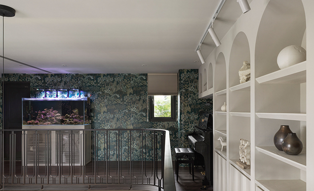 
游戏区——自然光影相偕绿意海水 敞亮疗癒的游戏空间

开放式双层设计的採光优势，令户外流泻的自然煦光充盈夹层，点亮弧形铁件栏杆的洗鍊细緻，及洁白拱型收纳牆的柔曲优雅，描绘如英式花园的高尚典雅意象。周围壁面选用花卉图样壁纸，包裹女主人细心照料的海水鱼缸，绿意与海蓝交织清新而略带神祕感的氛围，将大自然的生命力引入家中，激发孩子们无穷的想像力。于此，钢琴乐声与鱼群悠游的粼光掠影相伴，空间在艺术与自然之间流动，让生活多了几分诗意及童趣，更围塑一方家人共享的疗癒场所。
