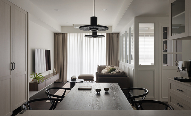 
本文由OPEN编辑部撰写

深木铺地浅木为牆，将小日子过成一幅有温度的素描！

浅木、白壁间，一道从容的秩序悄然展开——柜体的线脚收束空间的稜角，却又在玻璃格扇的透映裡，轻轻释放呼吸的宽裕。暗色木质自地坪沉潜而起，黑铁椅骨与百叶筛落的光影彼此应答，恰似水墨留白处偶然落下的几笔焦墨，点醒整幅素雅的构图。

日工设计 设计总监 王绍峰 採用轻浅涂料搭衬白壁，为二十一坪的居所铺设一张素淨的起居画布，天光得以循着柔和色调自在游走，不着痕迹地舒展小宅的视觉馀裕。足下，深色超耐磨地板沉稳落定，顺着动线一路延展至餐桌木纹及书房长案，偕同铁件线条、黑色吊灯的细腻勾勒相互应和，轻盈沉着之间酝酿出恰到好处的温润层次。书房一隅，百叶滤出层层叠叠的细碎光痕，窗畔卧榻上随意搁着的编织毯，静静诉说两人共居的默契， 让家不只是归处，更是一段为彼此悉心收整的舒心日常。
