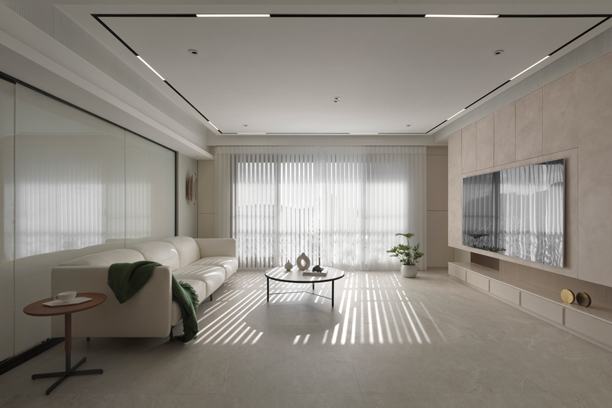 
客厅——曲弧展柜 平衡收纳与美学距离

此案将公共区域比例放大，成为家人情感交流的主要舞台。客厅宽间隙的电动片帘宛如时间的滤镜，随着四季更迭，让阳光在水泥灰纹理的地坪上恣意挥洒，织就不同的光影诗篇。沙发背牆窗畔旁的皮革立面散发低调质感，造型壁灯则投射出温柔的光晕，使每一刻都化作独特的艺术时光。 
