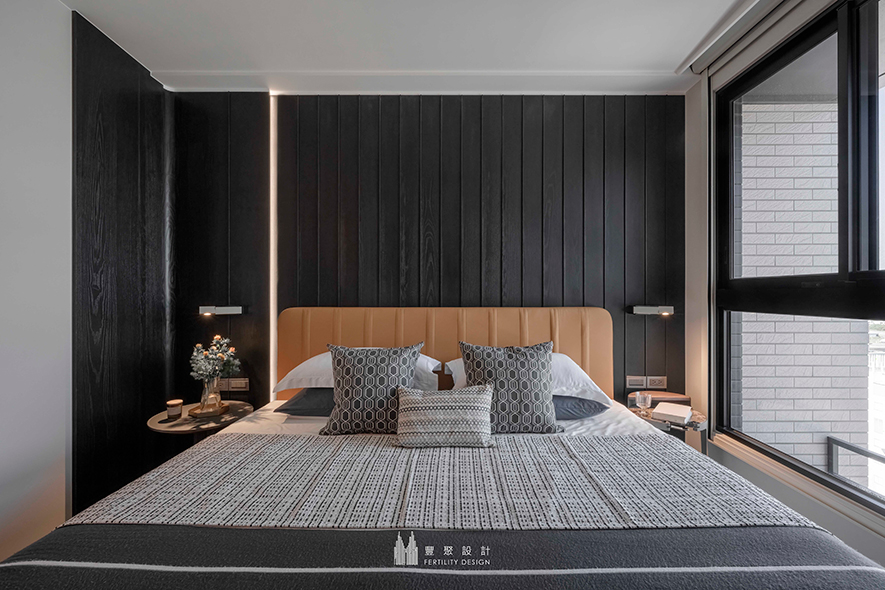 
主卧——阒黑木纹凋刻理性俐落端景 跳色轻盈亦能酝酿静谧氛围

主卧床头牆延续廊道的阒黑木皮材质，奠定宁谧平和的沉心环境，而木纹间倏地溢洒一道明灯，点亮深色中的朴润暖调，尔后携手床背板屋主锺情的漫片亮黄，运跳色设计为此处灌注活泼生命力，进而实现交融沉静及轻快的无压休憩场所。
