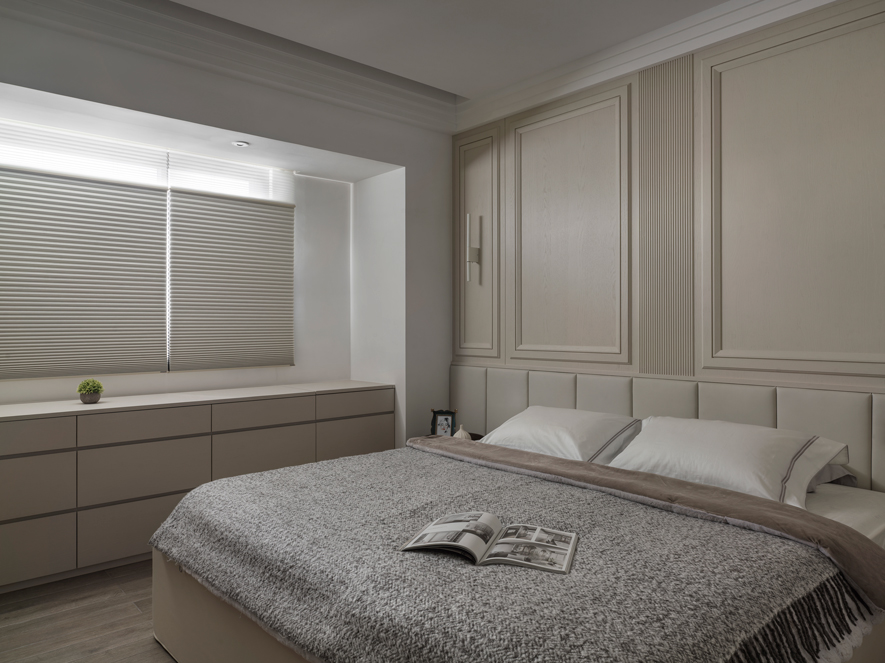 
主卧——贴心设计 缔造安眠休憩天地

主卧延续公领域的米色及线板造型，营造纯粹而宁静的休憩氛围。窗畔平台整合抽屉柜与梳妆区，柜内预留插座的贴心规划，使吹风机、电捲棒等电器随时供居者方便取用，令每个清晨与夜晚的梳理，都变得从容而优雅；后方的更衣间则与浴室相连，形成流畅便利的生活动线，让此处成为美好睡眠与悠閒晨昏而设计的私密天地。
