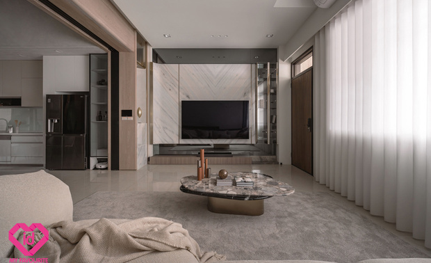 ▲客厅以香槟金髮丝纹镀钛饰条串连，与灯饰的金光呼应，灰镜电视牆收尾，打造如度假饭店般精緻场域，将屋主对悠閒优雅的生活想像精准具现。
