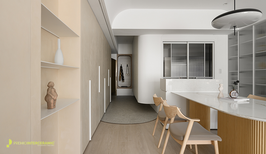 ▲玄关设木质圆框穿鞋椅兼具挂衣功能，搭配一旁圆弧茶镜营造简约的廊道端景；地坪採大面板水磨石砖呈现无缝质感，与室内木地板交界处以弧形镀钛铁件收边，呼应天花圆弧设计，为空间增添精緻亮点。
