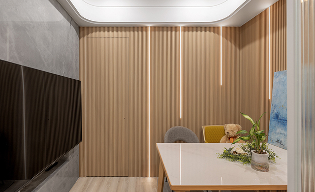 
玄关——入室光帷 藏露有序

推门而入，右侧长虹玻璃隔屏以半透光影温和划分内外界线，为来访者保留一方视线过渡的馀裕。光线穿过细腻纹理，在奶茶色调的玄关柜体上投映出斑驳光晕，柔和色泽与周遭温润木质相互呼应，为随身物品预留专属归处；左侧则是一字型厨房区域，以相同色系柜体延续明亮基调，白色檯面映衬明淨俐落的料理动线，镜面电器柜嵌入其中，倒映微光，入门视野在实用与美感间和谐共存。在这方寸之间，既是隔绝外界喧嚣的终点，也是归家卸下繁忙的仪式起始。
