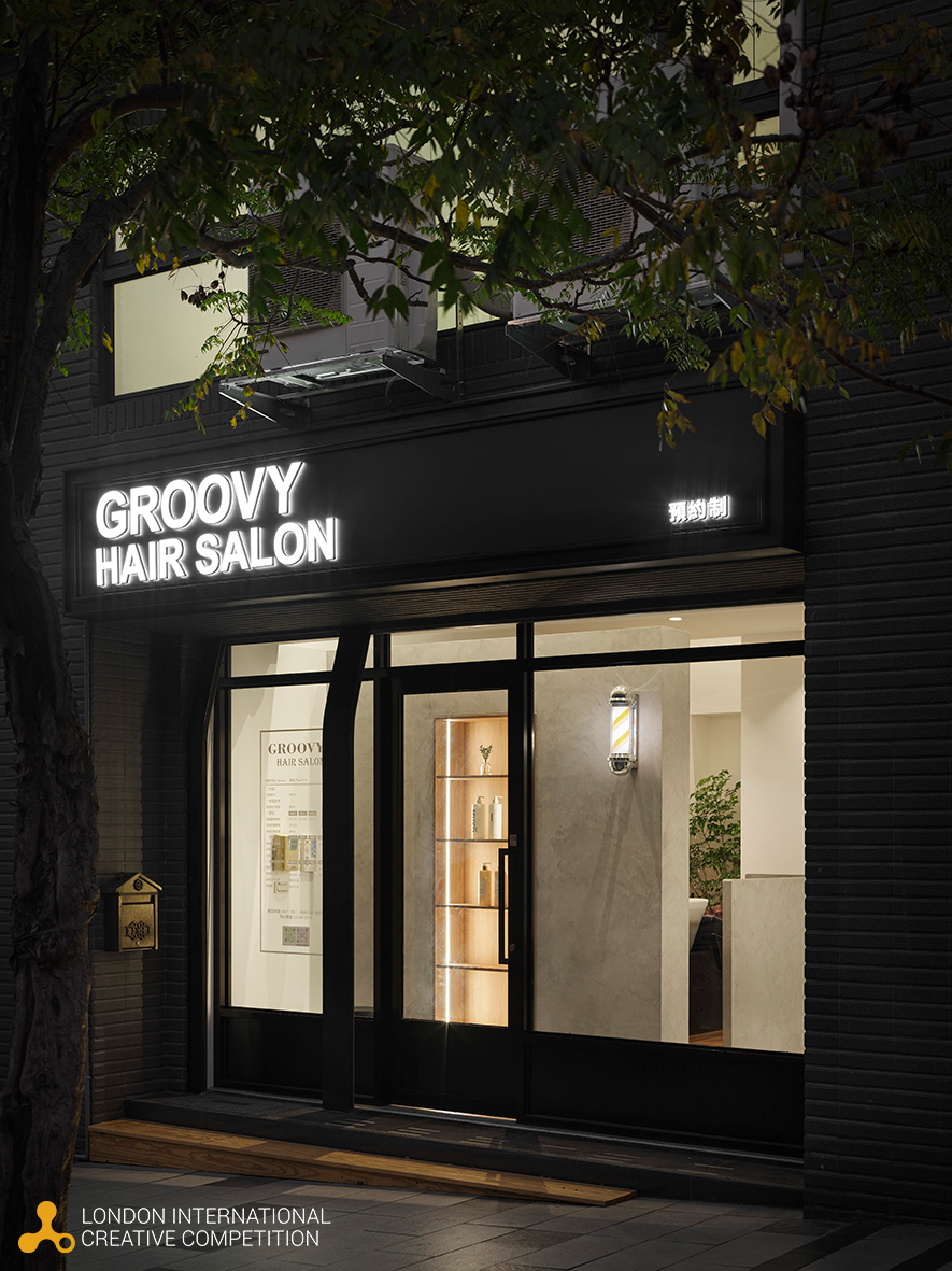 ▲理髮厅标志性的旋转灯设置于一楼洗头区外牆，不仅避免影响外部招牌的视觉设计，更成为室内别具巧思的造型亮点；墨绿色的磁砖柜檯清晰引导动线外，更呼应后方色彩丰富的商品展示区，吧台同时可遮挡部分员工休息区，维持整体空间的秩序与美感。
