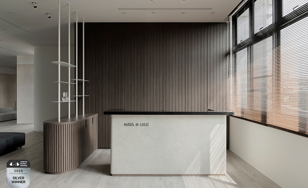 ▲入口柜体以大地色系特殊涂料铺叙沉稳底蕴，迎宾区域廊道则选用灰白色调，营造宁静舒心的过渡场域。接待柜台右侧大面窗引入自然光，与背后格栅式的实木条映照出阴影变化，衬托出自然温润质感。
