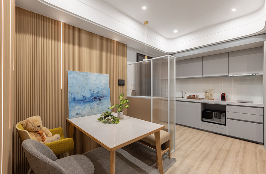 
本文由OPEN編輯部撰寫

材质交迭光影共舞 构筑疗癒身心的弹性场所！

曦光穿透长虹玻璃的朦胧纹理，在空间中缓缓流转，与奶茶色调与温润木质相互依偎，营造柔和宁静氛围；灰镜映照日常光影变幻，将有限空间延展成无垠想像，令视线在虚实之间自由呼吸；空气中飘散着兰草的清雅香气，为每个角落都披上一层诗意的面纱；无论是吧台边独享的晨间咖啡时光、餐桌前沉浸的午后阅读片刻，还是榻榻米上慵懒的黄昏观影时分，所有烦忧都烟消云散，取而代之的，是心灵被温柔包裹的安定感。

此案定位为设计师自用示范宅兼办事处，由 艾美幸福设计 设计总监 许捷甯 亲手操刀规划，将现代与日系元素融合，为小宅打造复合溷搭的独到美学。其间，长虹玻璃隔屏的灵动光感，搭配灰镜面反射的延伸放大效果，凝鍊「小而不侷促」的开阔视感；更藉由可弹性运用的榻榻米区、餐桌吧台的多重机能设定，以及架高区的垂直收纳巧思，实现「一空间多场景」的生活哲学。
