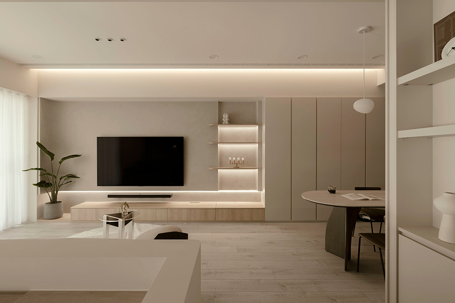 
客厅──巧勾弧韵 满溢和缓自适氛围

步入客厅，双层电视牆延续餐区柜体色调，自展示层架、主牆至窗畔勾起的弧面，齐整无间断的朴暖画面也勾起、渗入观者的心，杂乱思绪得以在此纯淨间沉淀，且多处量体下缘倾泻的线性明光，不仅偕同纱帘淌入的户外天光，衬托主牆特殊涂料的纤细质感，更强化悬浮视觉效果，实现亲和宜人、艺韵满盈的舒适生活场所。
