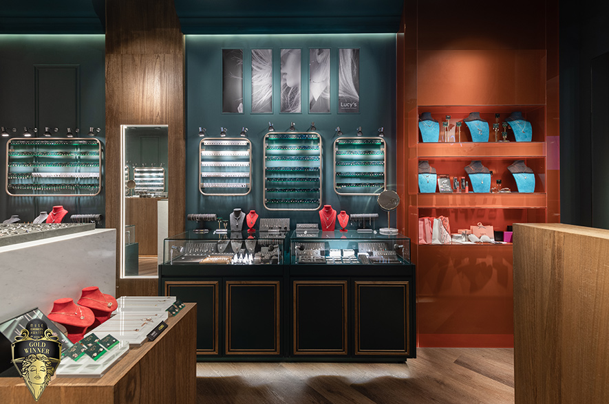 ▲展示区中段增设的L形橘色烤漆玻璃结构，藉由反射面提升亮度与画面层次，并作为狭长格局的视觉节点，转换空间节奏并带有舞台佈景感；两侧牆面的红色壁灯与吊灯，则以典雅造型与入口处的水晶灯遥相呼应，聚焦牆面上主力商品的同时，也营造充满热情活力的购物氛围。

华苇轩
纬纶设计 设计总监
电话：02-2701-8631
地址：台北市中山区中山北路三段26号11楼之3
信箱：weilun.ltd@gmail.com
网址：https://www.weilundesign.com/

OPEN Design 动能开启传媒：https://www.openworld.tv/