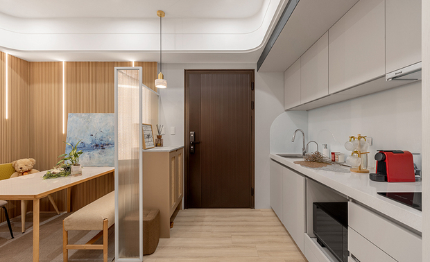 
客餐厅——迭影延伸 场景流转

踏进公领域，目光首先被格栅牆面吸引，嵌入的垂直灯带自细密木条间流洩而出，光影层迭交织，为空间铺陈日系沉静的韵律基调；旁侧大理石主牆与吧台旁的灰镜组合，巧妙将有限空间向深处延展，令视线在层层倒影中找到开阔出口，压迫感瞬间消弭无踪；前方，一桌两椅一凳的简约配置，打破传统客厅的沙发印象，让餐区化身为弹性舞台：当电视萤幕投映简报内容，餐桌瞬间转为专业会议场域，当艺术画作斜倚格栅牆面，此处又摇身成为美学品味的展演空间，日常在多重场景间流畅转换，处处蕴藏生活的无限可能。
