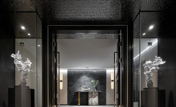 | 轻启门扉 流转在心间

一处院门，一处景
黑与白的诗意共栖
柔和的灯光，宛若银烛般的秋光
恍如不经意步入山间小径
融于大自然的怀抱
独特的入户背景墙勾勒出独有的艺术氛围
波光粼粼的天花，仿佛微风轻抚的水面
太湖石造型雕塑以其独特的姿态，屹立于此
感受到时光的延绵和心灵的回归
入门之礼如花开成蔓延
