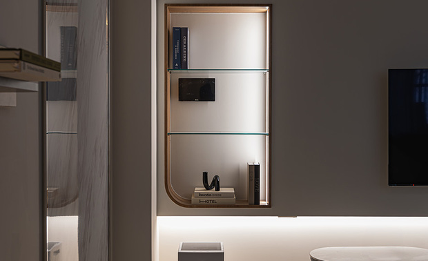 
客厅——浅色调交织的素淨诗意 异材质对话下展现层次美感

大面积的象牙白与浅驼色在此舒柔交汇，圆润饱满L型沙发如云朵轻盈佔据视觉焦点，编织抱枕、毛绒织品层迭其上，为纯淨基调注入温暖触感；前方浅色圆形造型茶几、弧形电视柜，结合黑色铁件框架，在悬空皓白的电视牆下带出视觉重心，达成色彩的和谐，酝酿一室柔软安定；一旁，大面石纹磁吸板的细腻灰白纹理，宛如行云流水一般悠然延展，将典雅气韵凝结于牆面，同旁侧木质悬浮层板、立面构成异材质的优雅对话，在造型壁灯的光泽映照下，谱写当代简约与生活温度兼容的温馨居家时光。
