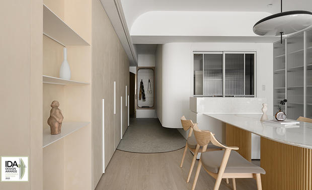 ▲玄关设木质圆框穿鞋椅兼具挂衣功能，搭配一旁圆弧茶镜营造简约的廊道端景；地坪採大面板水磨石砖呈现无缝质感，与室内木地板交界处以弧形镀钛铁件收边，呼应天花圆弧设计，为空间增添精緻亮点。
