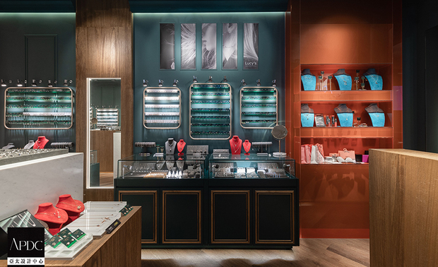 ▲展示区中段增设的L形橘色烤漆玻璃结构，藉由反射面提升亮度与画面层次，并作为狭长格局的视觉节点，转换空间节奏并带有舞台佈景感；两侧牆面的红色壁灯与吊灯，则以典雅造型与入口处的水晶灯遥相呼应，聚焦牆面上主力商品的同时，也营造充满热情活力的购物氛围。


华苇轩
纬纶设计 设计总监
电话：02-2701-8631
地址：台北市中山区中山北路三段26号11楼之3
信箱：weilun.ltd@gmail.com
网址：https://www.weilundesign.com/

OPEN Design 动能开启传媒：https://www.openworld.tv/