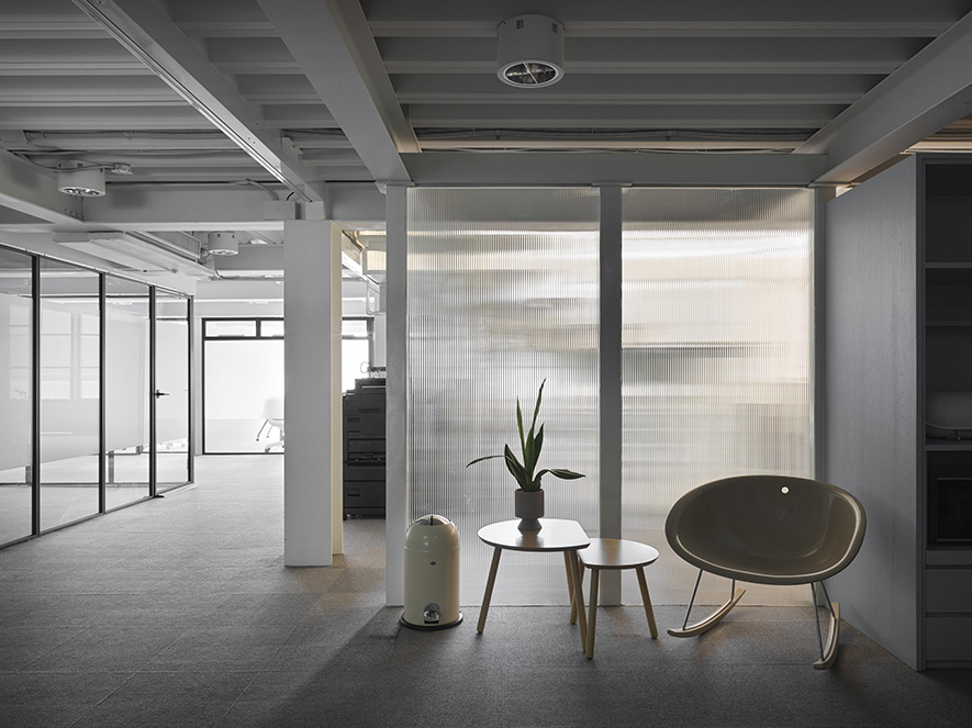 本文由OPEN编辑部撰写

打破冷硬框架，沉静却充满暖意的环保科技办公基地！

灰白基调铺陈空间的沉静底蕴，浅木色调的温润质地柔化科技业办公室的锐利感；跳色家具点缀其间，为理性办公场域注入恰到好处的活力，既不喧宾夺主，又在视觉上形成愉悦节奏感；U型会议桌围合出思维交流场域，玻璃隔间的透光性与灵活开合赋予空间呼吸弹性，时而私密专注，时而开阔通透，共同编织充满生命力的创新天地。

本案作为科技公司的总部，业主期望打破科技产业固有的冷硬形象，澄境设计 设计总监 郑抿丹 遂以大地色系的艺术漆牆奠定稳雅基底，融合木质的柔和、金属的俐落与皮革的精緻，层叠一番冷暖相容、带有精细光泽与柔软触感的空间表情；配合红蓝绿对比色家具、自然垂坠绿植点缀，注入活泼生机之外，其丰富植栽亦在整体无甲醛建材与节能系统的基础上，增强淨化空气、调节温湿作用，为员工创造健康舒适的绿色办公环境，同时向到访者传递企业应尽的社会责任与前瞻思维。
