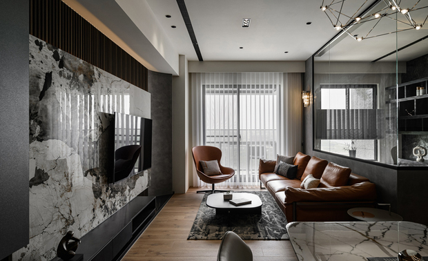 ▲客厅採黑白大板砖与木格栅双层电视牆，前后材质拼接展现冷冽与柔润的对比美学；圆弧窗畔设计则柔化立柱，增添空间流动感与趣味。

