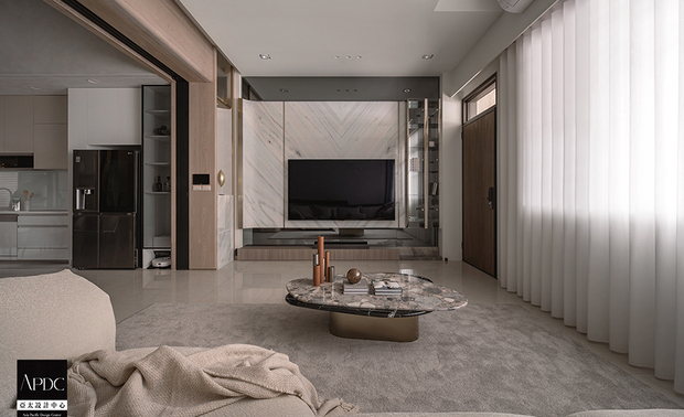 ▲客厅以香槟金髮丝纹镀钛饰条串连，与灯饰的金光呼应，灰镜电视牆收尾，打造如度假饭店般精緻场域，将屋主对悠閒优雅的生活想像精准具现。
