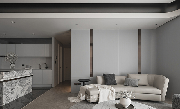 
客厅——垂直线条勾勒当代风骨 圆润软装围塑阖家时光

转身面向客厅，整面大理石电视牆矗立，满幅铺展沉稳雅緻格调；且两侧特别配置圆弧收边的金属饰条，垂直线条自天花延伸而下，内嵌暖光自其中透出，为石材牆面渲染暖润光华，也在明暗之间注入几分凋塑感；上方天花则以深色线条框界，并施以圆弧转角处理，再次呼应牆面的金属收边，共同营造流畅而不失层次的美感。纵然纹理丰富却不显杂乱，反而因材质的一致性与细腻线条收边而显得沉静有序。

对向沙发区选用浅色调软装，圆润的造型与石材的刚硬质感形成对比，搭配圆形茶几与深色单椅，与地面人字拚木地坪相互呼应，围塑适合阖家相聚的场域。在冷暖色调的交织中，生活在此找到舒适的节奏——无论是三五好友的閒谈时光，或是独自一人静静品茗，随手翻阅一本书、斟上一杯茶，便足以让身心在石材与光影的陪伴下安然沉淀，这方居所始终以最从容的姿态，承接着每一个值得珍藏的生活片刻。
