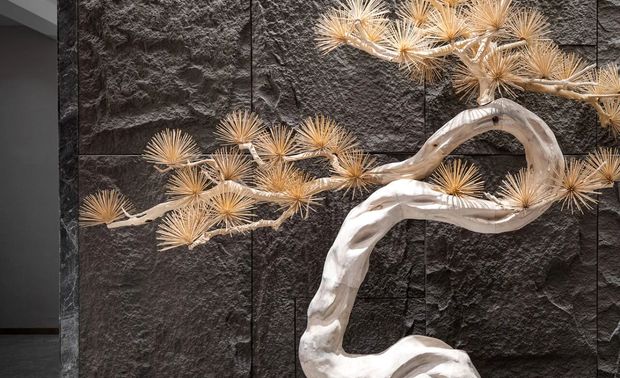 玄关采用极具中国风元素展现的是一种含蓄的美，枝干遒劲的迎客松、散落有序的石头搭配沉稳有质感的黑色隔断墙，中式玄关设计成为开门欢迎客人的第一道风景。